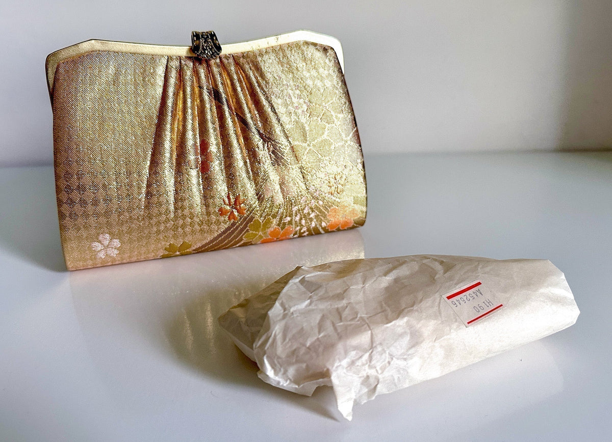 Gold vintage Japanese silk clutch bag beside the paper bundle found hidden inside it