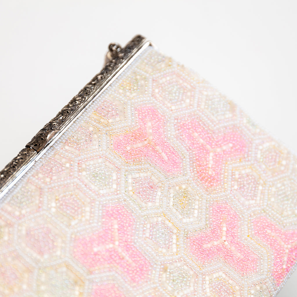 close up of vintage Japanese beaded bag showing beadwork in white and pink and the ornate silver metal frame closure