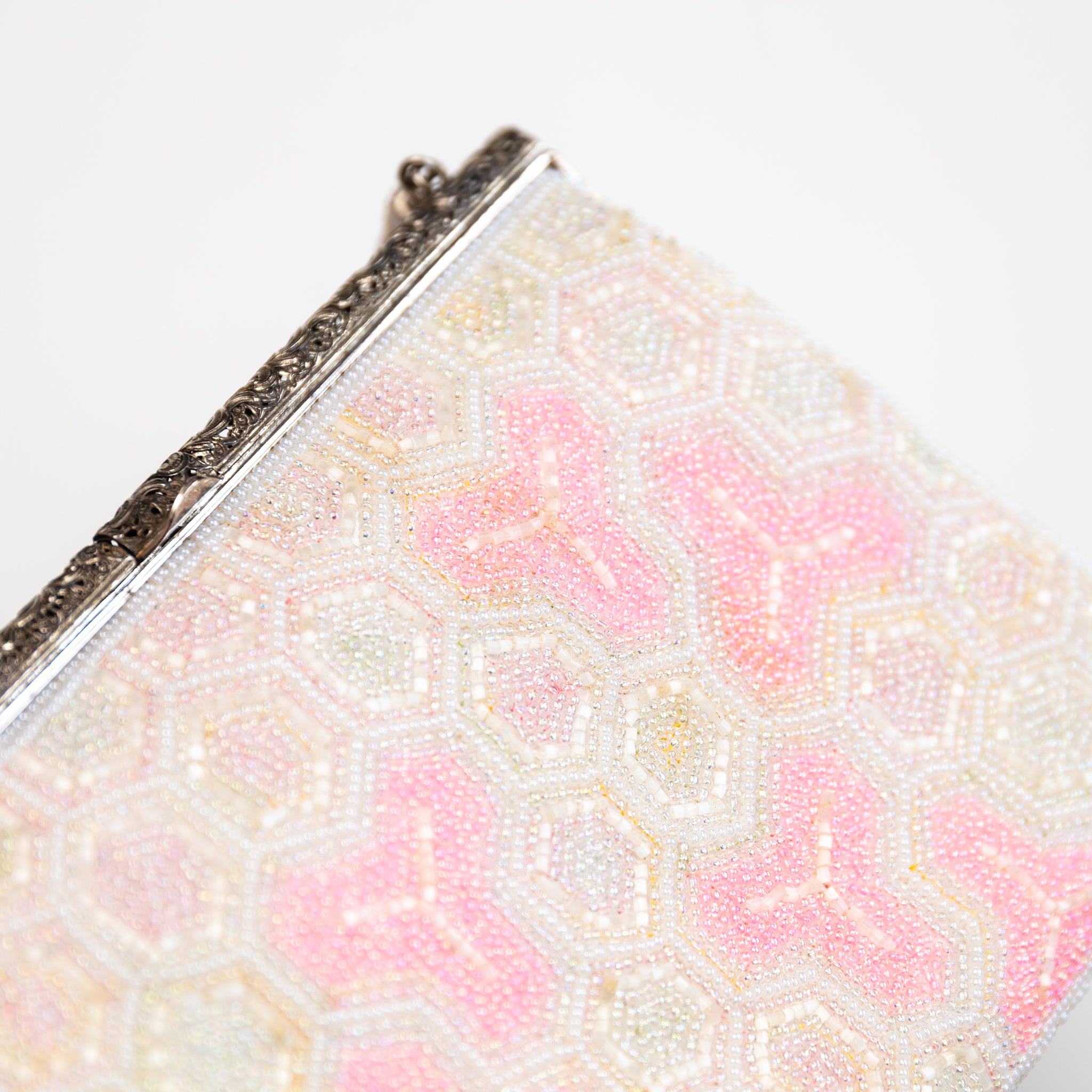 close up of vintage Japanese beaded bag showing beadwork in white and pink and the ornate silver metal frame closure