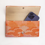 Open orange Japanese silk foldover clutch shown with iPhone 14 Pro Max for scale