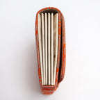 Side view of orange and gold Japanese silk foldover clutch showing concertina edge and age spot