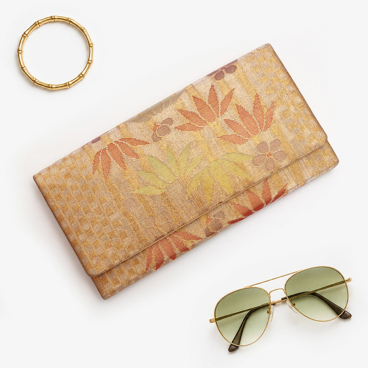 Metallic bronze-gold Japanese kimono silk envelope clutch with bamboo and floral design, shown in styled flatlay
