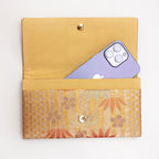 Open bronze-gold Japanese silk envelope clutch shown with iPhone 14 Pro Max for scale