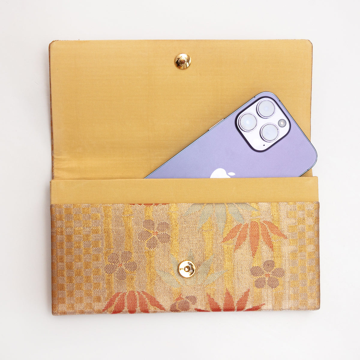 Open bronze-gold Japanese silk envelope clutch shown with iPhone 14 Pro Max for scale