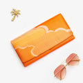 Metallic orange vintage Japanese silk foldover clutch with single gold cloud design, shown in styled flatlay