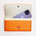 Open metallic orange Japanese silk foldover clutch shown with iPhone 14 Pro Max for scale