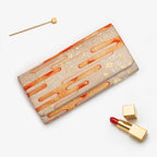 Pale gold Japanese kimono silk envelope clutch with orange kasumi mist and gold floral motifs, shown in styled flatlay