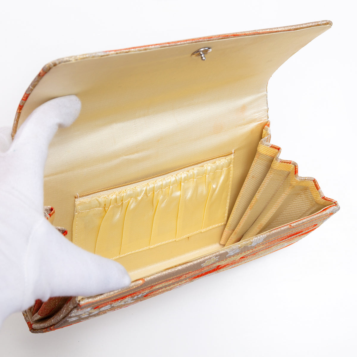 Cream silk interior with two pockets inside, one with gold trim, vintage Japanese envelope clutch, age spots on concertina edge interior.