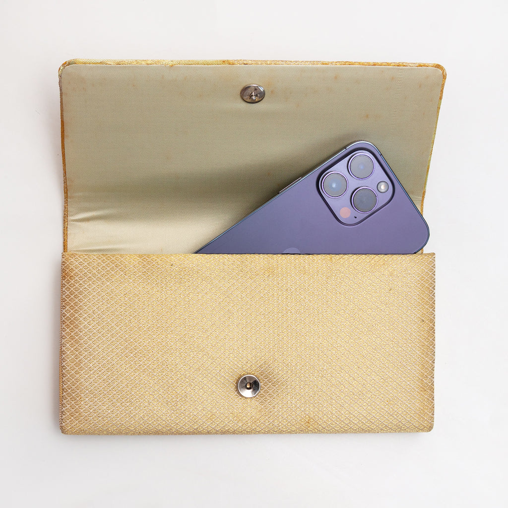 Open gold Japanese silk foldover clutch shown with iPhone 14 Pro Max for scale