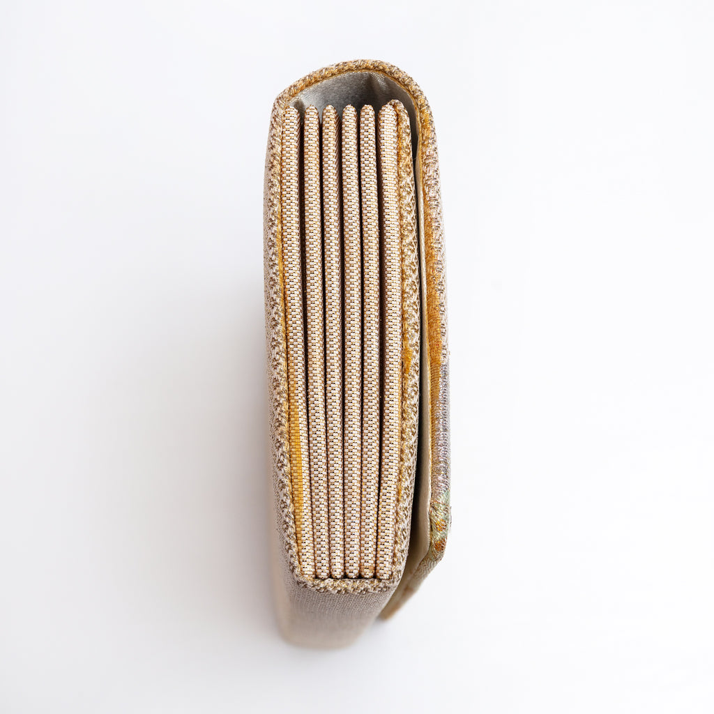 Side view of gold Japanese silk foldover clutch, woven gold and white silk.