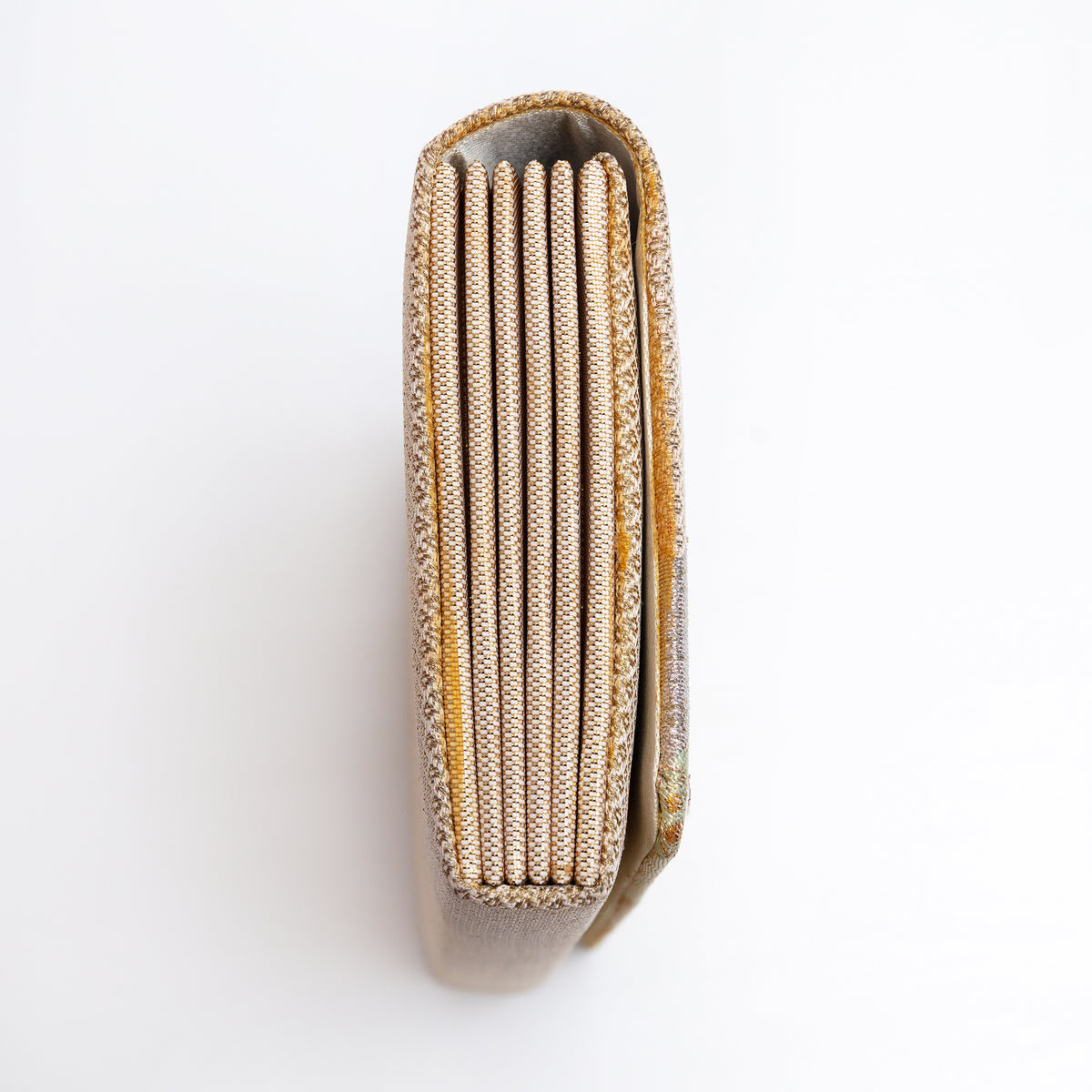 Side view of gold Japanese silk foldover clutch, woven gold and white silk.