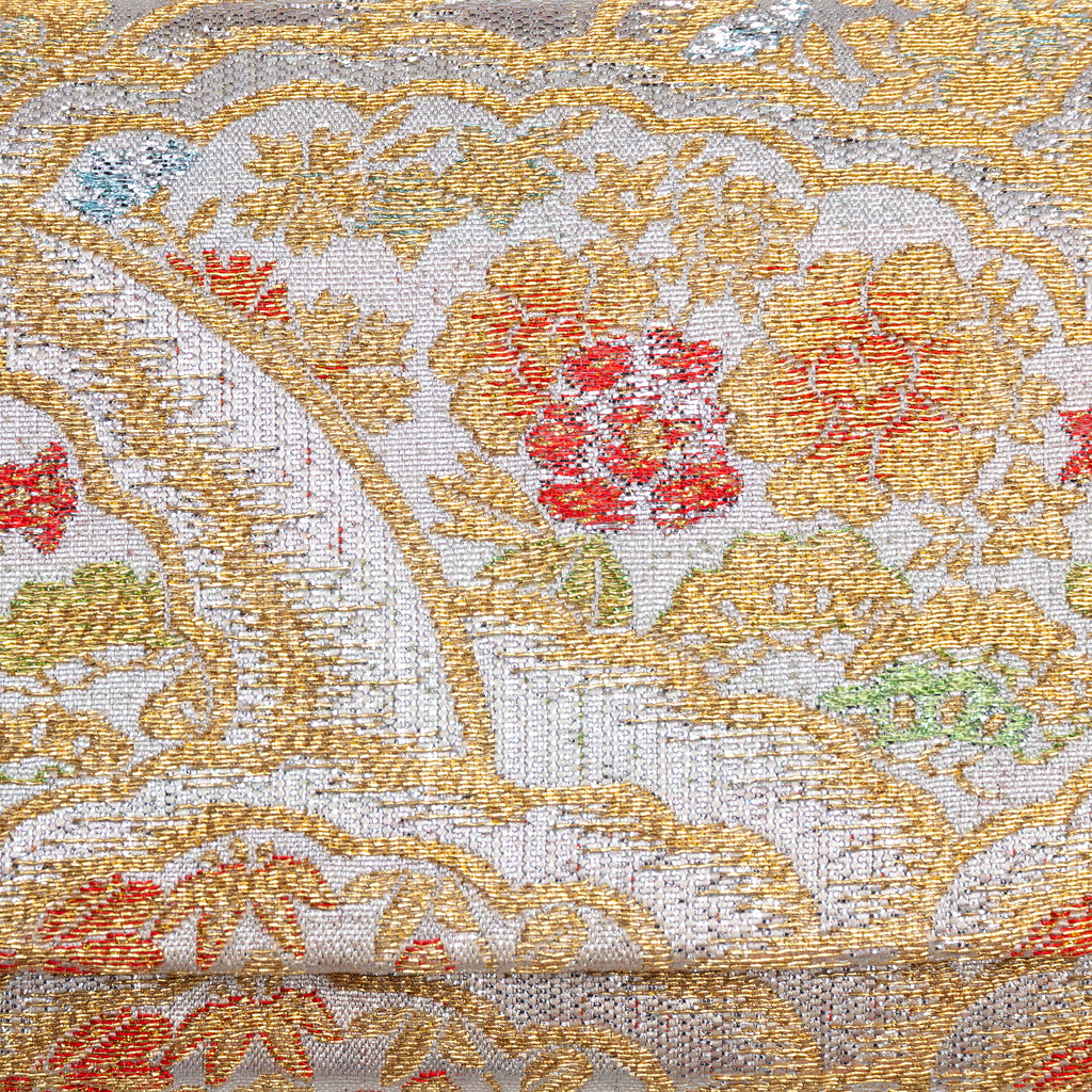 Close-up of metallic silver and gold kimono silk with peony, bamboo and pine details in red, blue and green