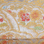 Close-up of metallic silver and gold kimono silk with peony, bamboo and pine details in red, blue and green