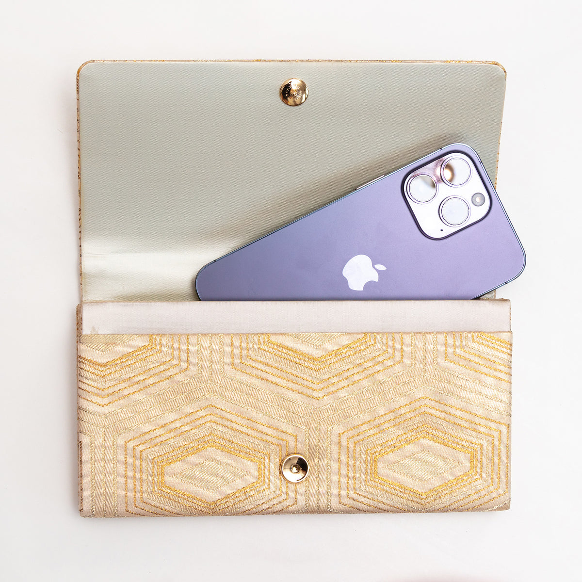 Open pale gold Japanese silk foldover clutch shown with iPhone 14 Pro Max for scale