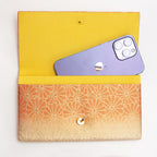Open gold and orange Japanese silk foldover clutch shown with iPhone 14 Pro Max for scale