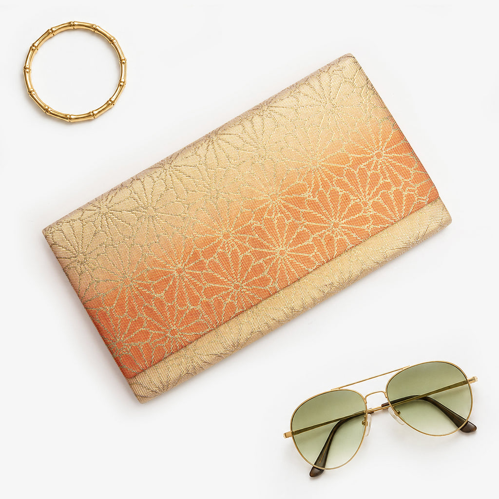 Gold and orange Japanese silk foldover clutch with chrysanthemum ombré design, shown in styled flatlay