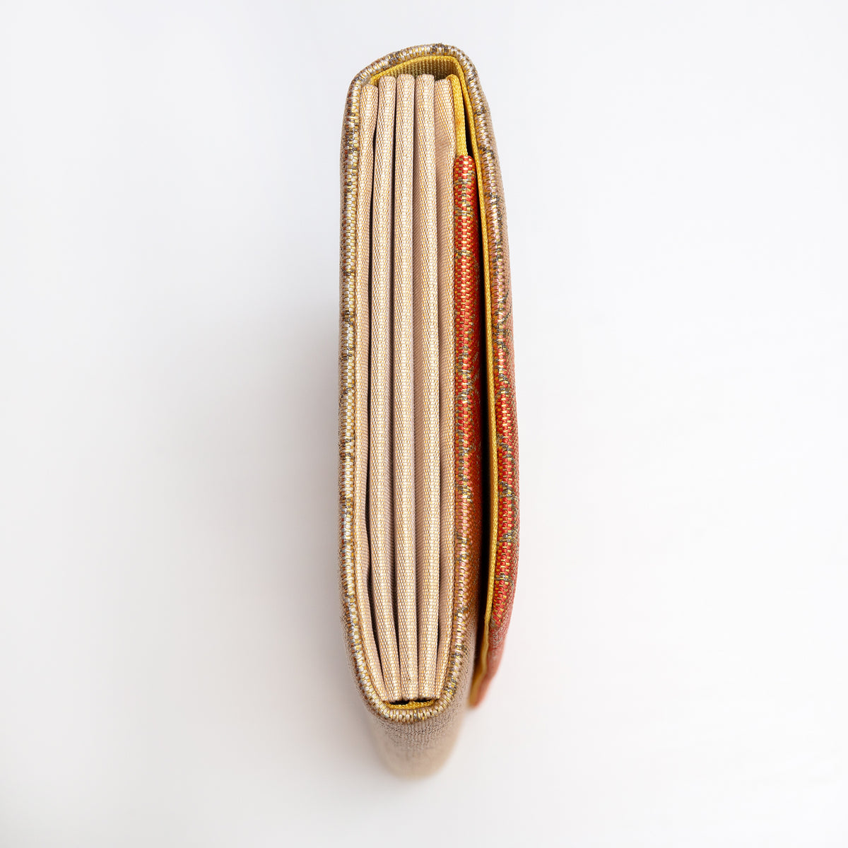 Side view of gold and orange Japanese silk foldover clutch with woven gold silk concertina side panels