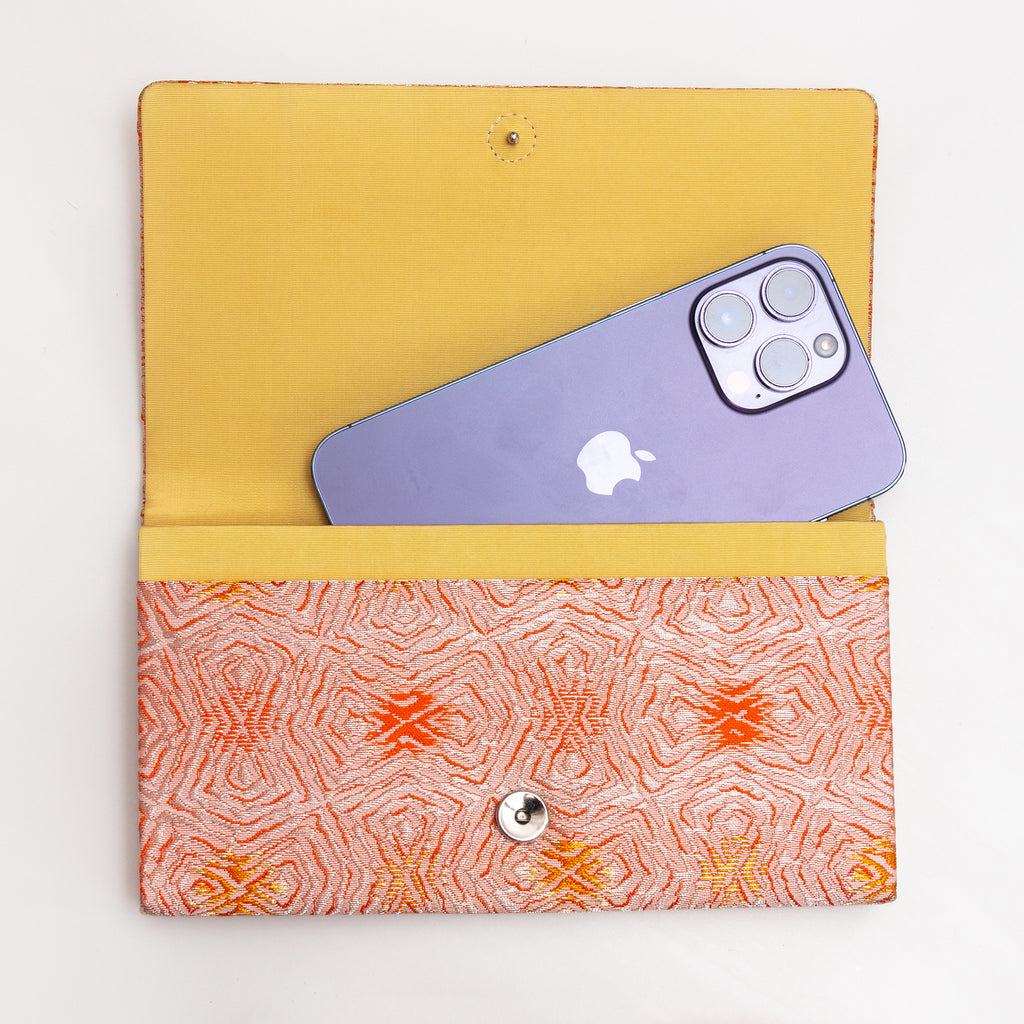Open peach and silver Japanese silk envelope clutch shown with iPhone 14 Pro Max for scale