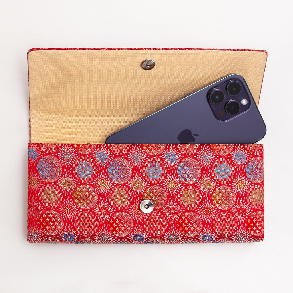 Open vermilion red Japanese silk envelope clutch shown with iPhone 14 Pro Max for scale