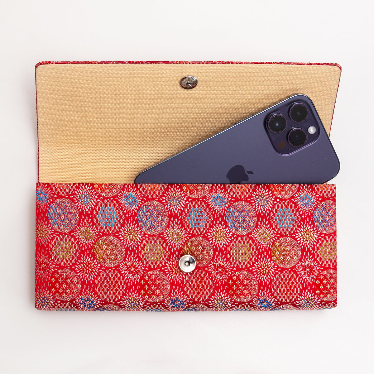 Open vermilion red Japanese silk envelope clutch shown with iPhone 14 Pro Max for scale