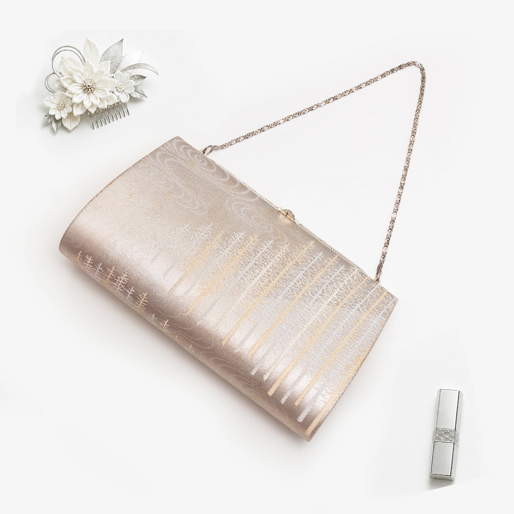Pale gold and silver Japanese kimono silk clutch bag  with trees pattern in a styled flatlay on white.