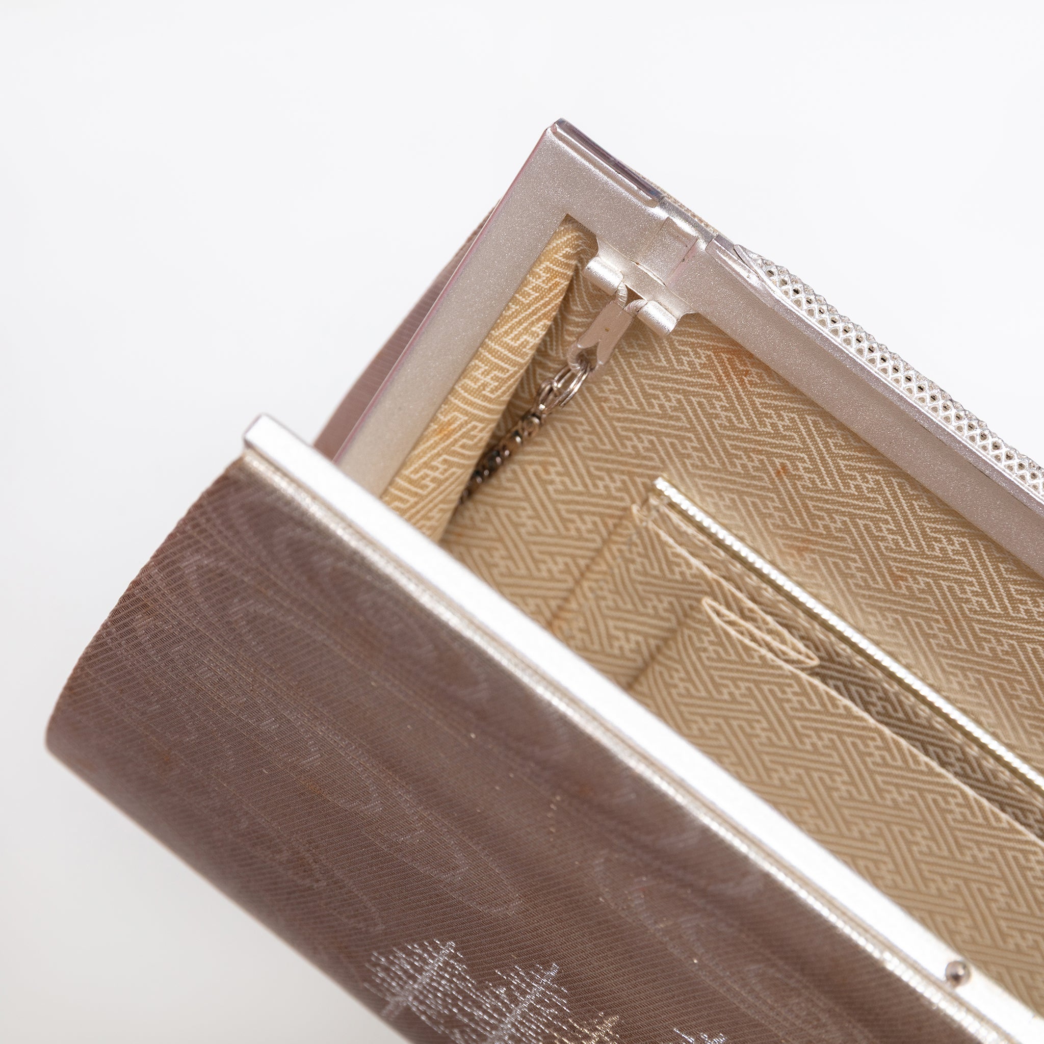 Pale gold sayagata silk lining with interior pockets inside vintage Japanese clutch bag, strap hinges tucked in