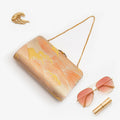 Orange gold Japanese kimono silk clutch bag with Araumi wild waves motif in styled flatlay on white background.