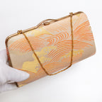 Japanese kimono silk clutch bag with gold-tone frame shown at an angle with gold chain strap