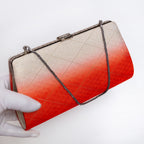 Orange and cream Japanese kimono silk clutch bag held at three-quarter view with silver-tone chain extended