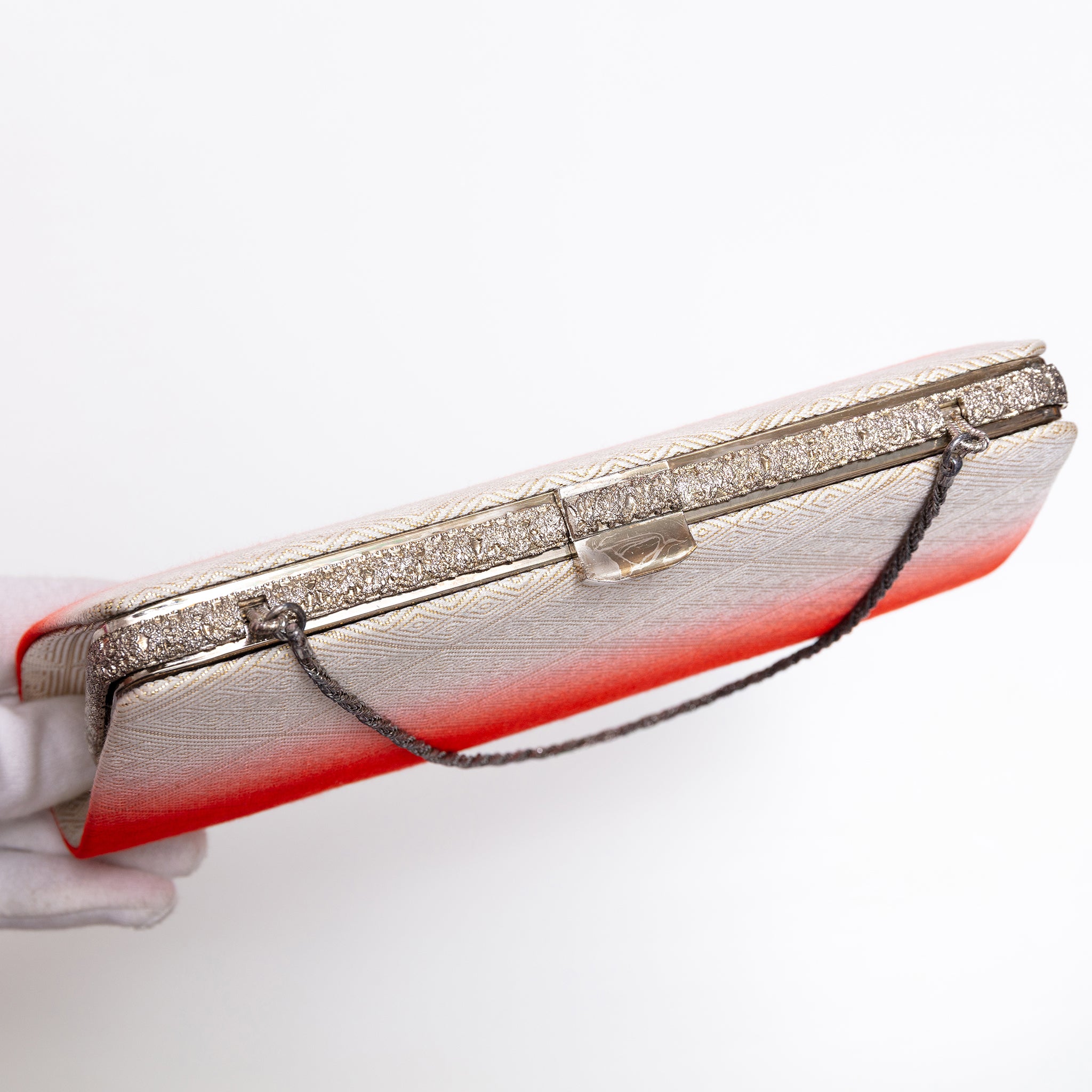 Top view of silver-tone clasp, textured silver frame and chain strap on vintage Japanese silk clutch