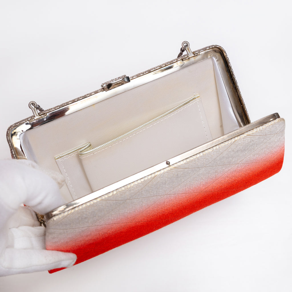 Open vintage Japanese silk clutch with white silk lining with one interior pocket showing with silver trim