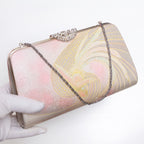 Iridescent phoenix kimono silk clutch bag held at three-quarter view with silver-tone chain extended, pink and gold silk brocade, vintage 1970s Japanese.