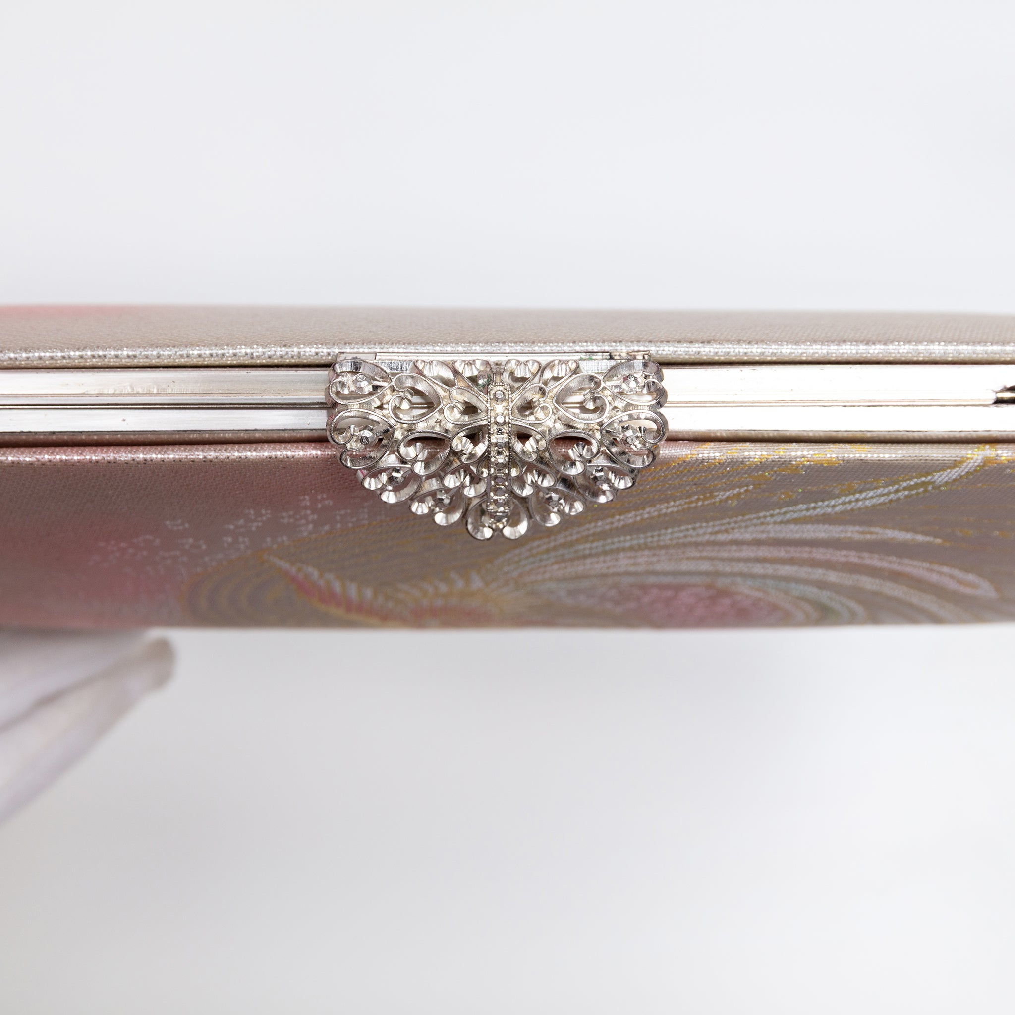 Close-up of statement marcasite silver-tone clasp with heart-shaped details on a vintage 1970s Japanese silk clutch bag in pink and silver