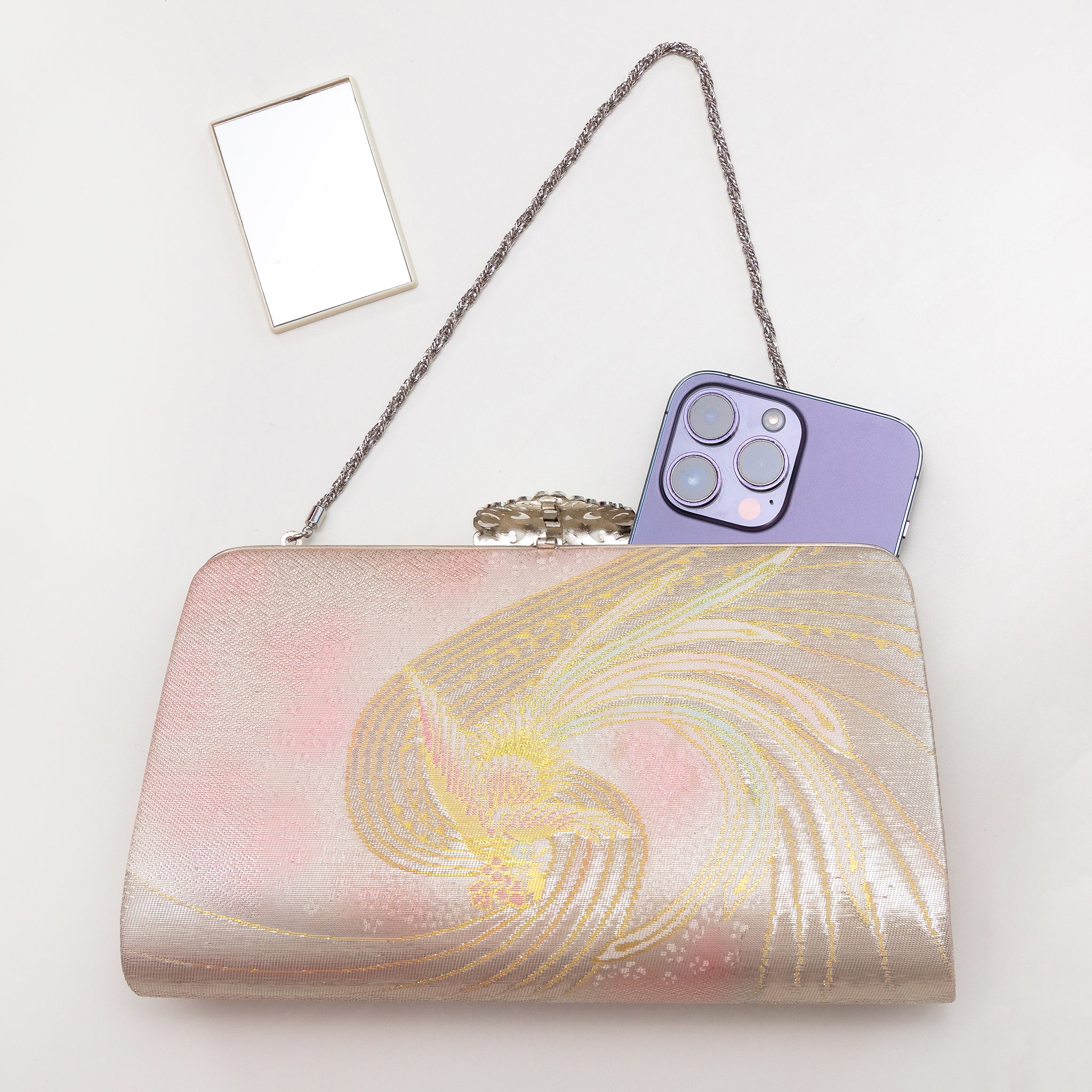 Iridescent Japanese phoenix clutch bag shown with iPhone 14 Pro Max for scale. Mirror included with bag.