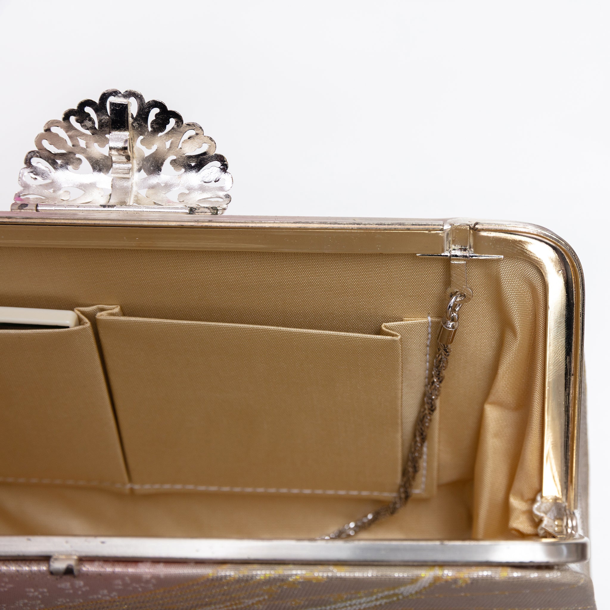 Close-up of fold-away chain hinge inside silver-tone metal frame of vintage Japanese kimono clutch bag, showing silk lining and interior pockets with original mirror