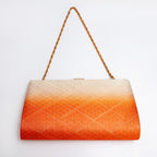 Back view of a structured evening clutch bag with a warm orange ombre gradient and an embossed geometric diamond pattern, featuring a gold chain shoulder strap and a small gold clasp at the top, set against a plain white background.