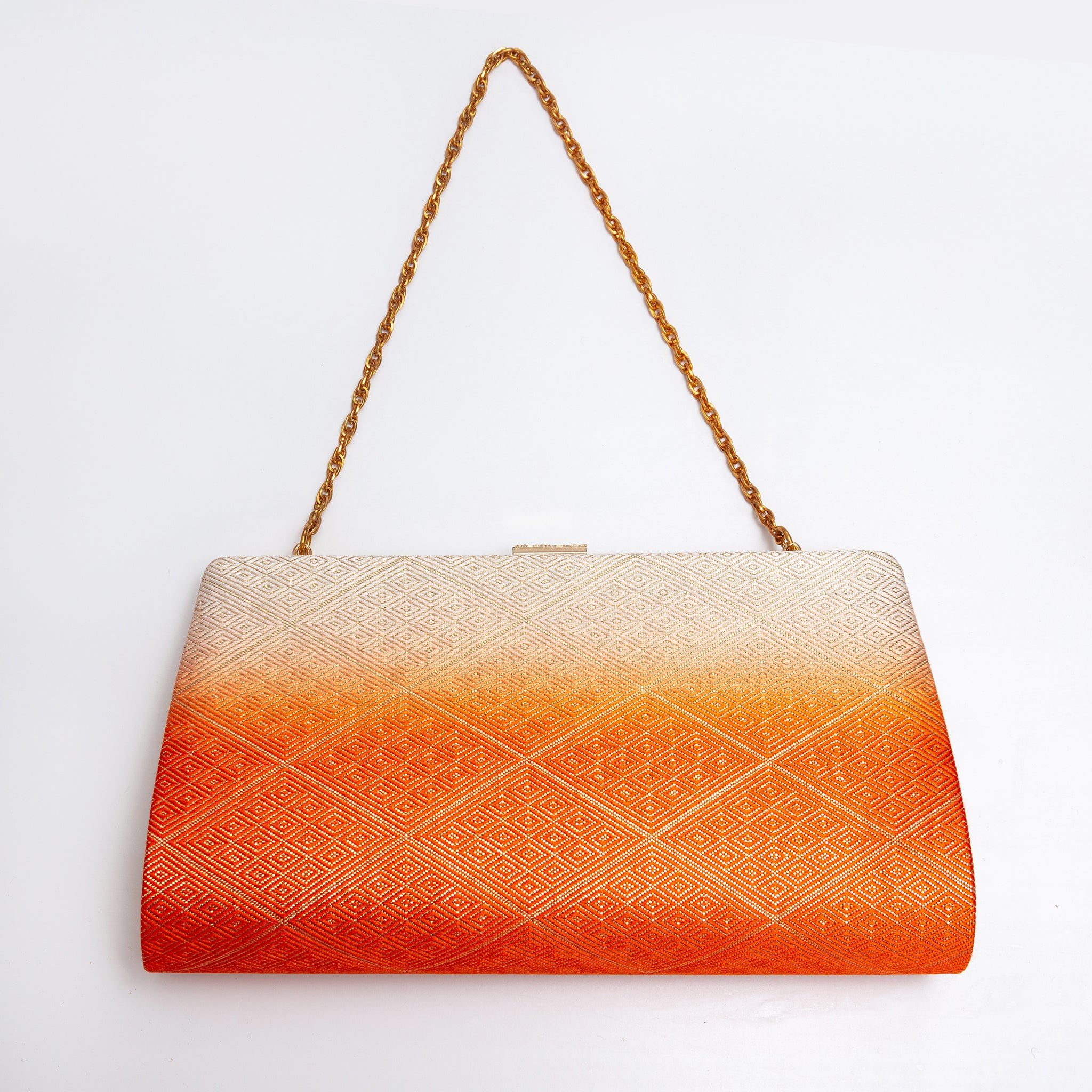 Back view of a structured evening clutch bag with a warm orange ombre gradient and an embossed geometric diamond pattern, featuring a gold chain shoulder strap and a small gold clasp at the top, set against a plain white background.