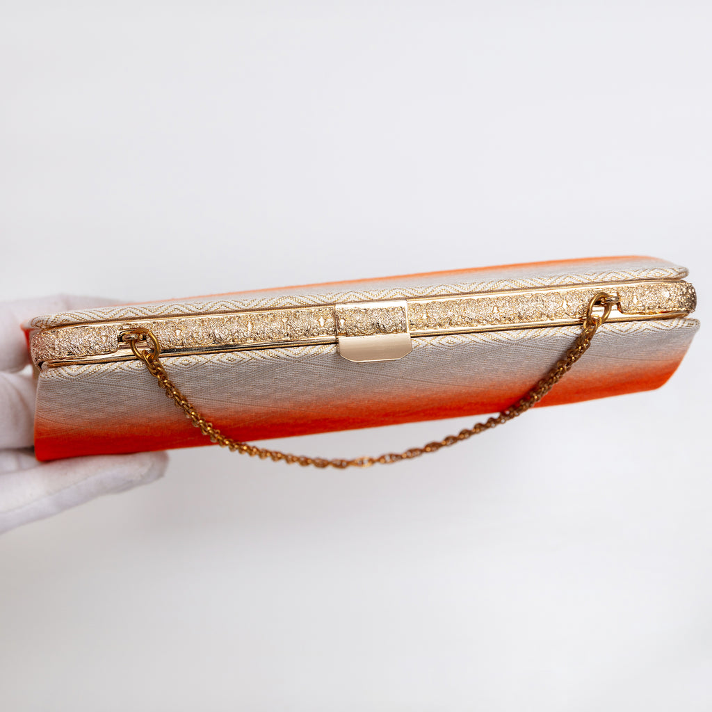 Top view of gold-tone clasp and textured gold-tone frame on vintage Japanese clutch bag. Gold chain strap.