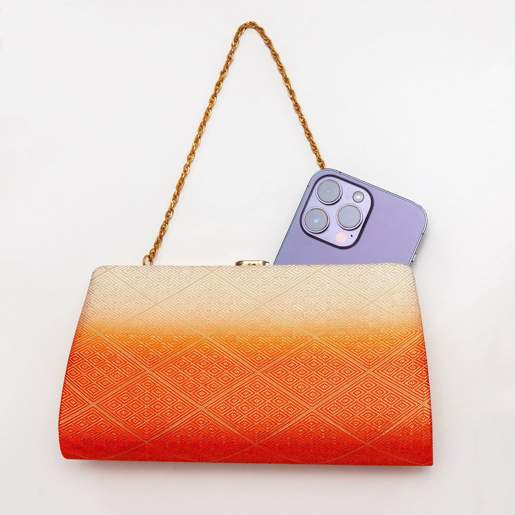 Orange and cream Japanese kimono silk clutch bag shown with iPhone 14 Pro Max for scale. Orange to cream ombre with gold geometric diamond pattern design.