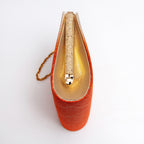 Side view of orange and cream Japanese kimono silk clutch bag with metallic gold silk side panel and textured gold tone bag frame and gold chain strap.