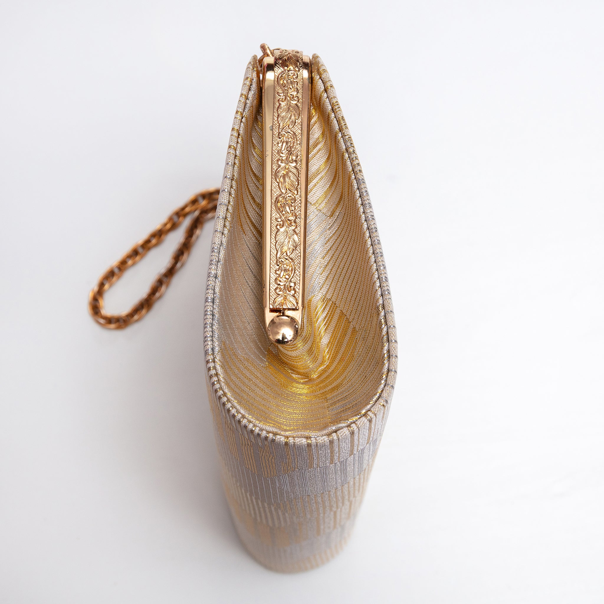 Side view of gold and silver Japanese kimono silk clutch bag, side panel in patterned gold silk, metal bag frame is textured with leaf pattern. gold chain strap.