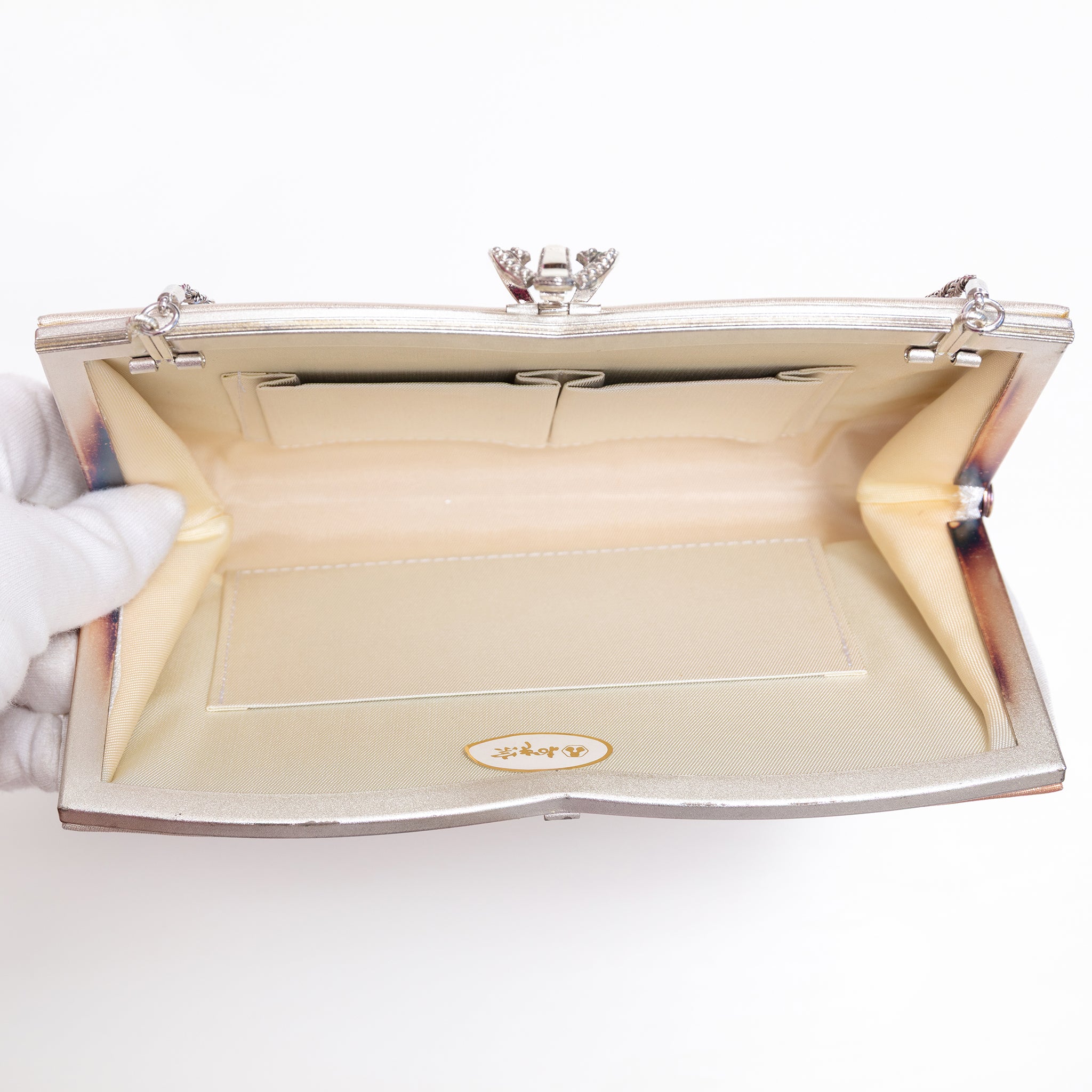 Open vintage Japanese silk clutch bag with silver-tone chain extended, cream silk lining and original paper sticker inside bag.