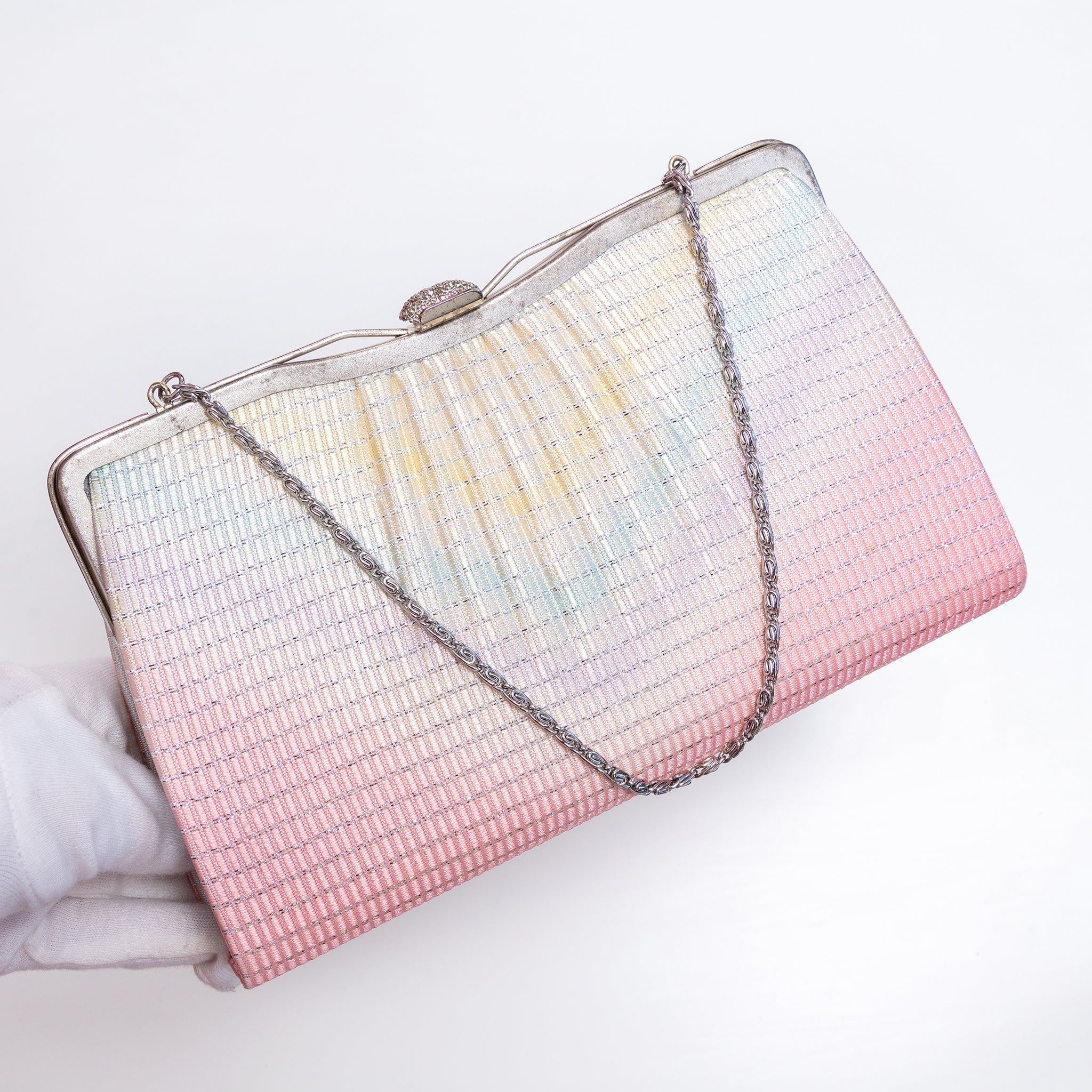 Pastel rainbow kimono silk clutch held at three-quarter view with silver-tone chain extended. Textured metallic finish, fancy silver clasp and chain strap.