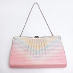 A vintage Japanese 1970s silk evening clutch bag with a pleated, textured surface featuring a pastel rainbow gradient fading from pink at the bottom to light blue and yellow at the top. It has a silver-tone metal frame and a silver chain shoulder strap, photographed against a plain white background.