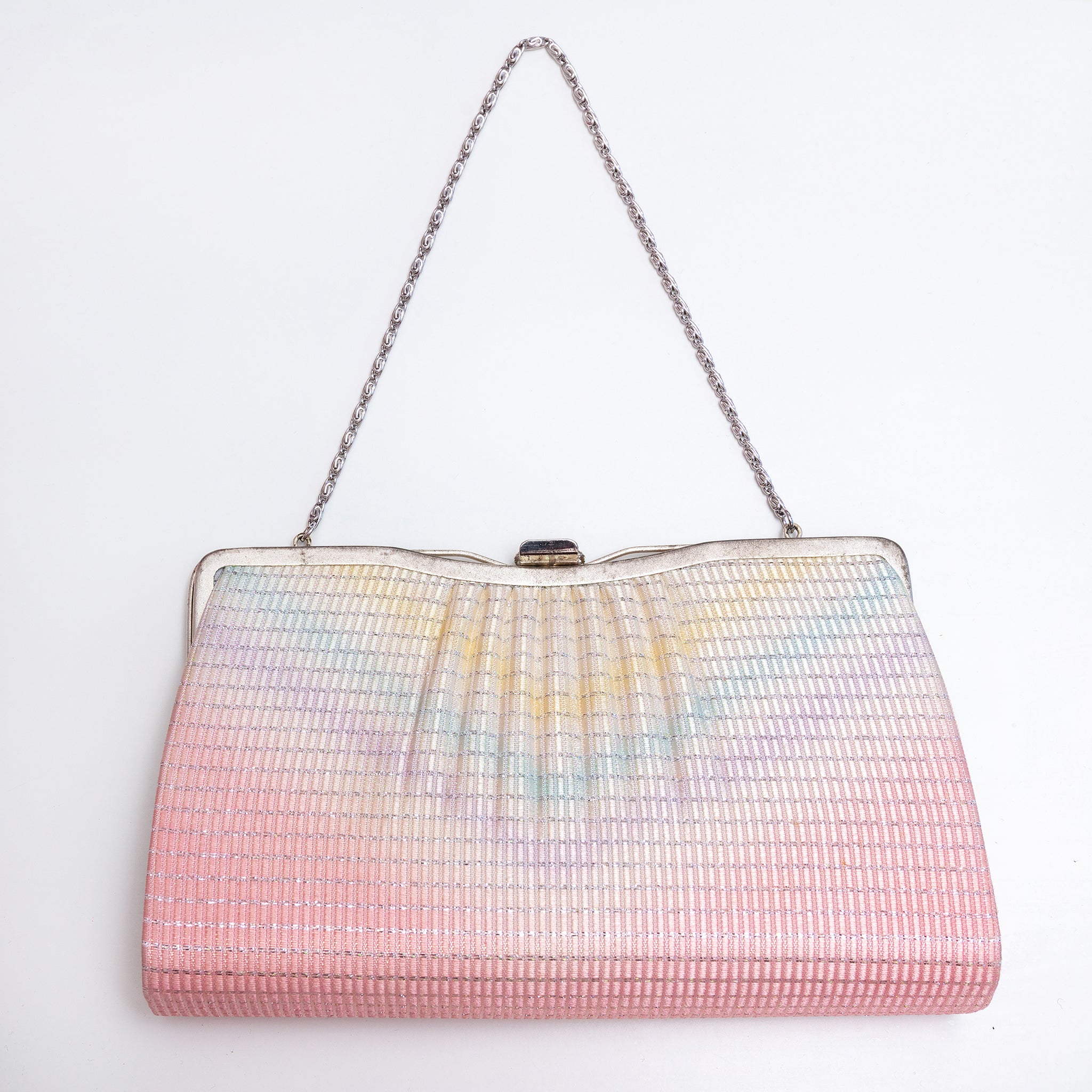 A vintage Japanese 1970s silk evening clutch bag with a pleated, textured surface featuring a pastel rainbow gradient fading from pink at the bottom to light blue and yellow at the top. It has a silver-tone metal frame and a silver chain shoulder strap, photographed against a plain white background.