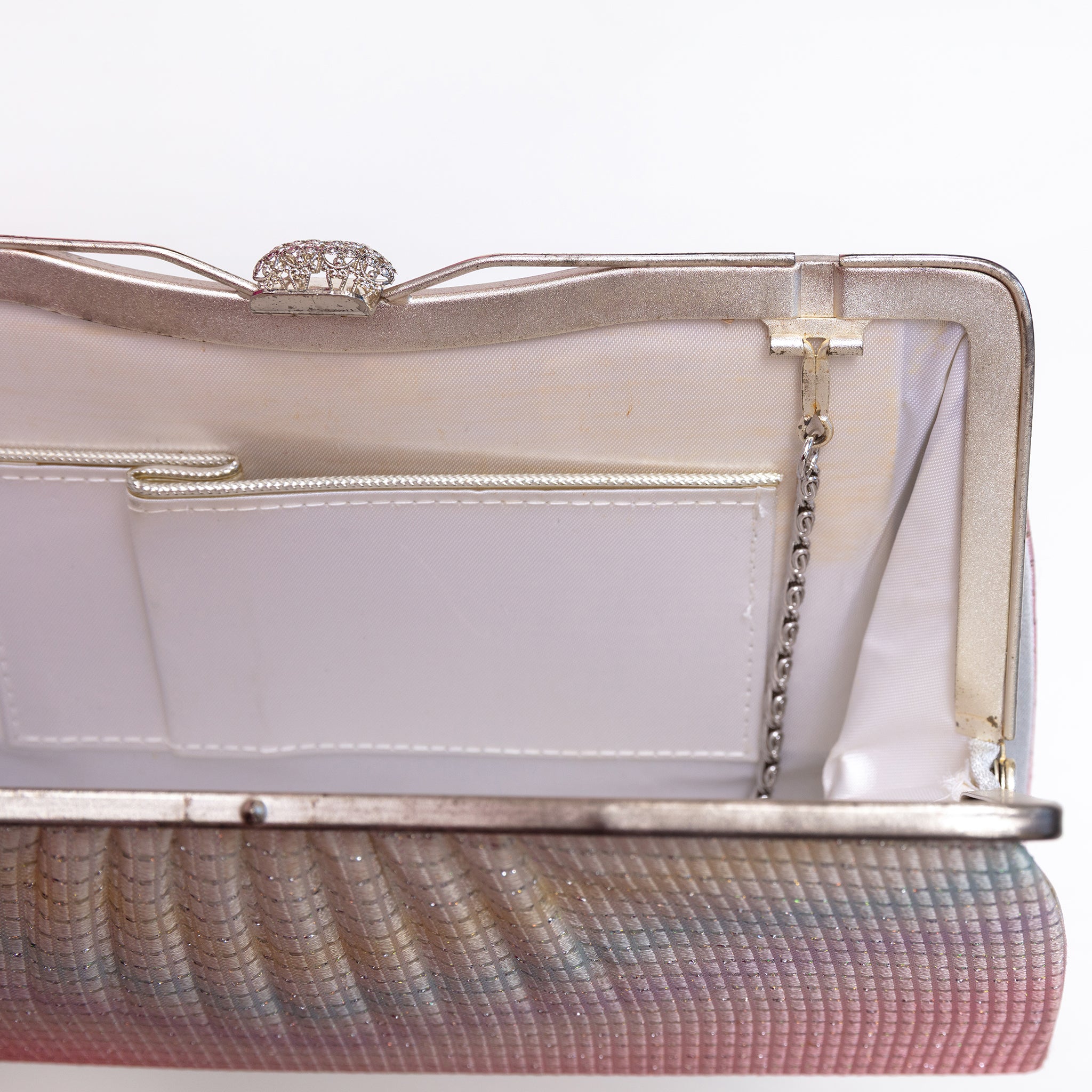 Close-up of fold-away chain hinge inside silver-tone metal frame, white silk lining