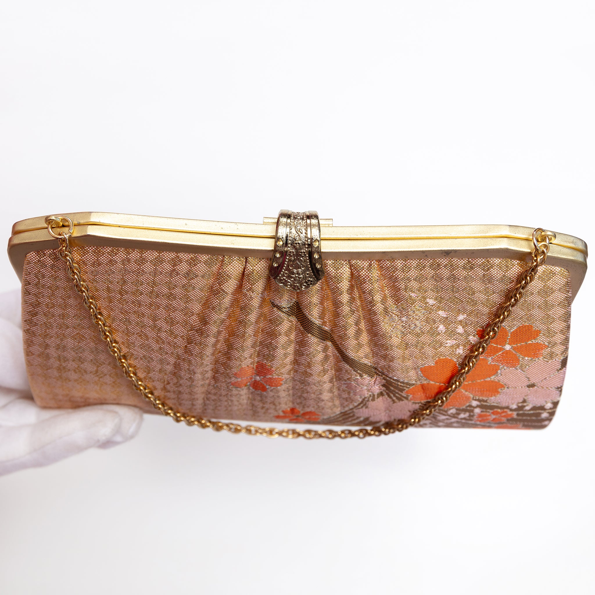 A vintage clutch purse with a gold-tone metal frame, pleated gold and orange silk checked pattern with crane and blossom. Fancy gold clasp and gold chain strap.