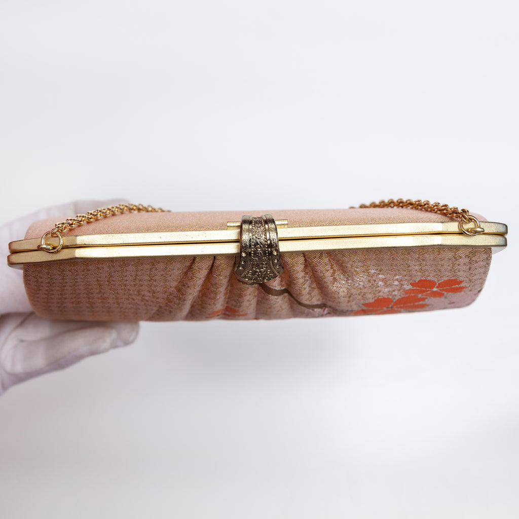 View of vintage clucth from above showing the chain strap coming out of the bag and the fancy old tone clasp and plain frame.