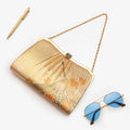 Metallic gold Japanese kimono silk clutch bag with flying crane and orange cherry blossom design, shown in styled flatlay