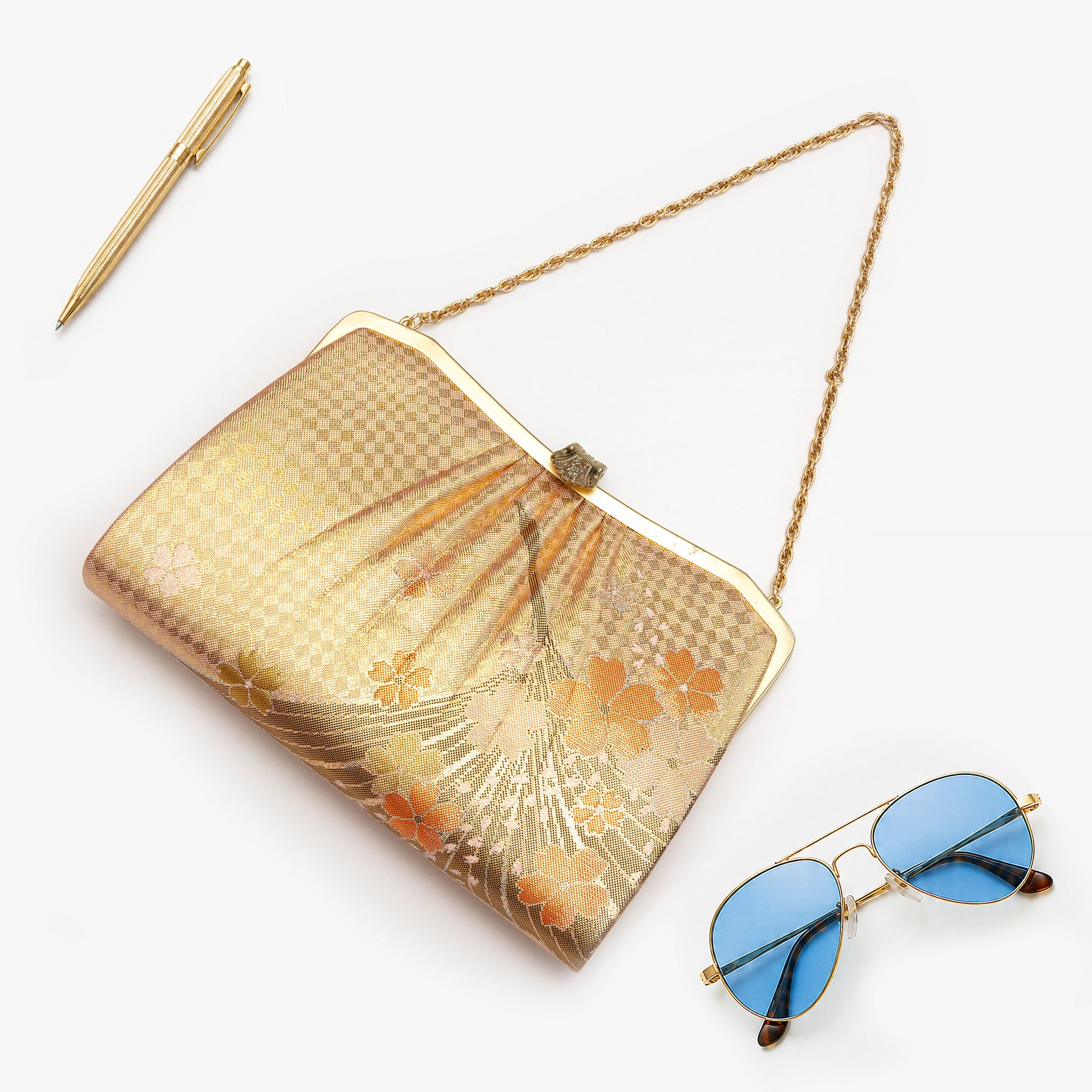Metallic gold Japanese kimono silk clutch bag with flying crane and orange cherry blossom design, shown in styled flatlay